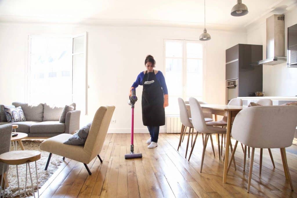 A cleaner helps vacuuming the parquet floor- hiring a cleaner in south london