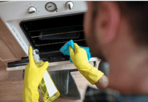 man cleaning oven