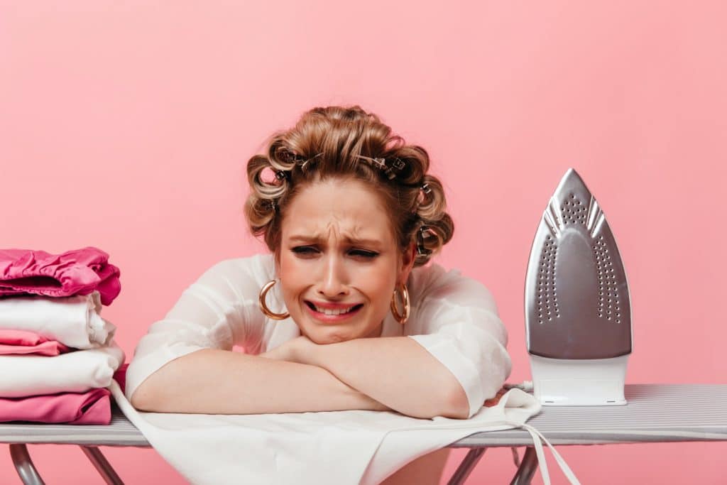 Girl with hair curlers leans on ironing board and cries-ironing board cover