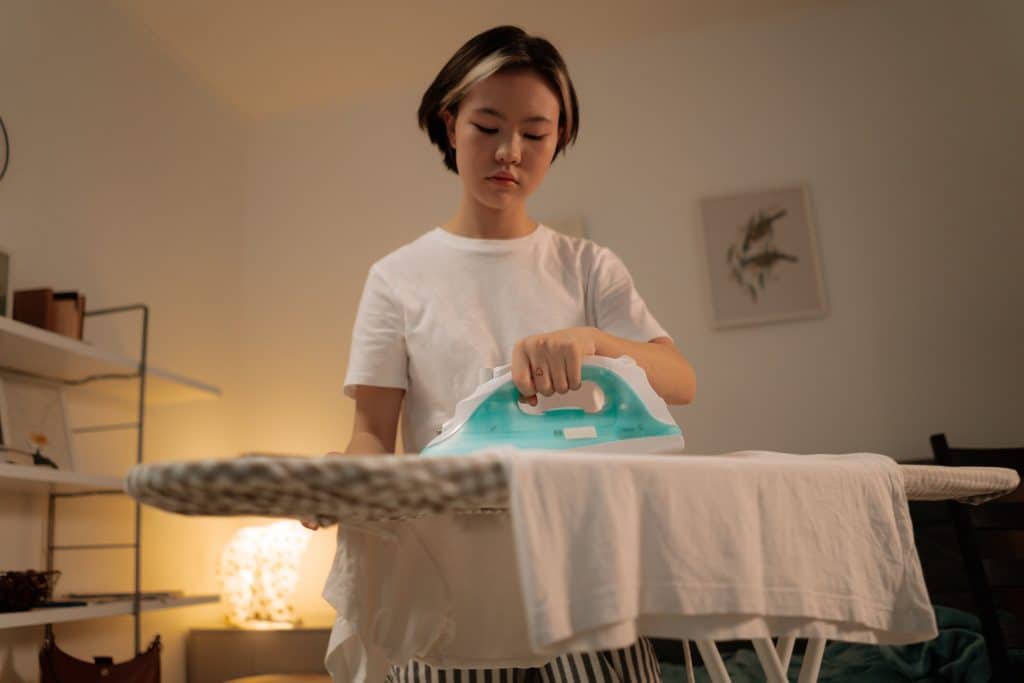 young Woman Ironing Clothes - How to iron on patches ? Get the best results - follow this guide