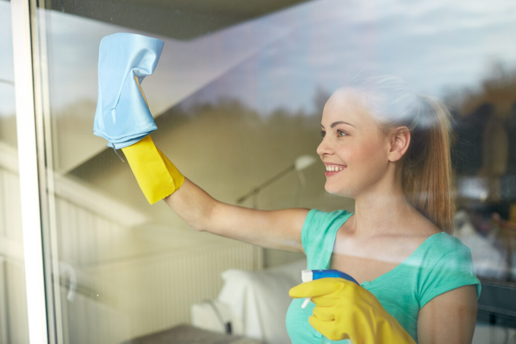 woman cleaning windows with a rag- house cleaning guide 