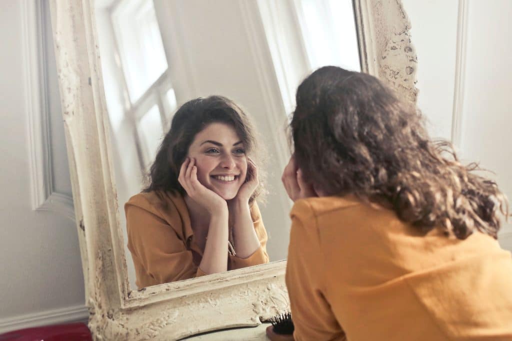 a woman smiling at her reflection in the mirror -clean and organized Home