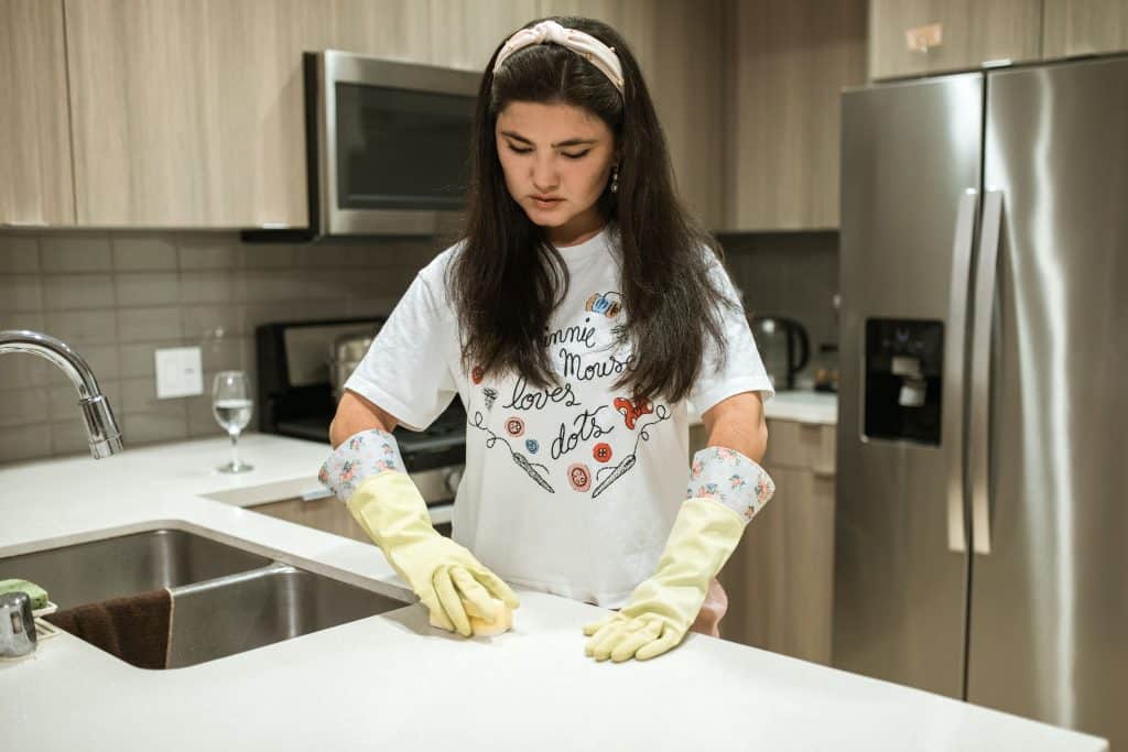 Woman cleaning a kitchen with yellow gloves