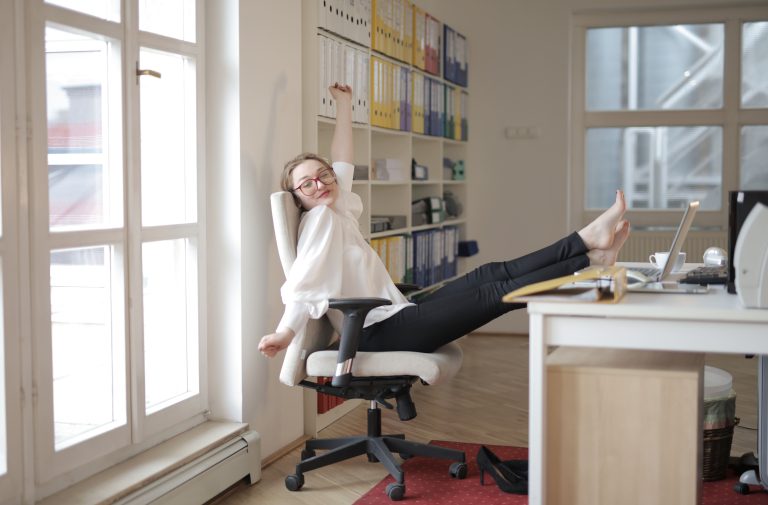 dreamy-female-employee-relaxing-with-feet-on-table-in-office