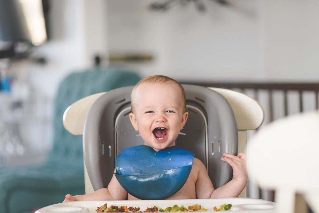 baby with a blue bib eating  - baby proofing-how to baby proof your home