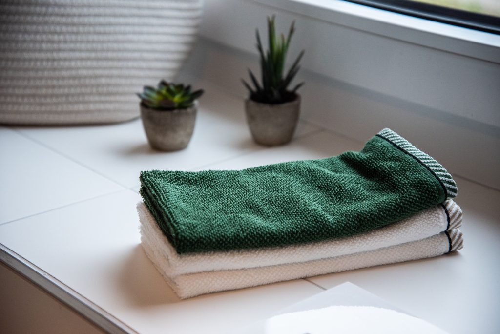 green and white folded towels-how often should you wash your towels