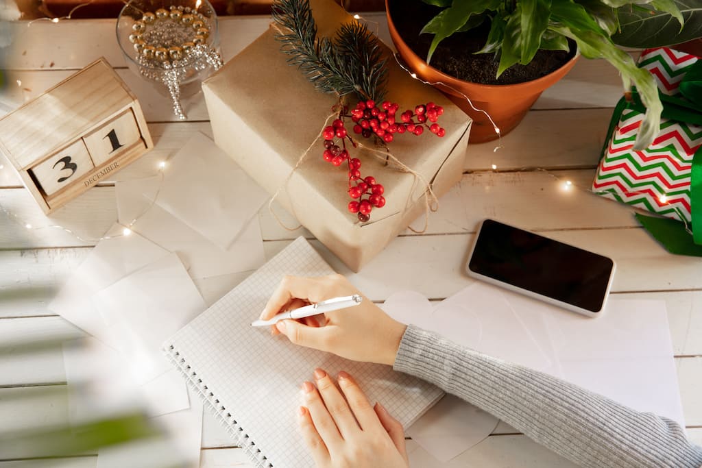 woman planning pre-Christmas checklist with pen and notepad
