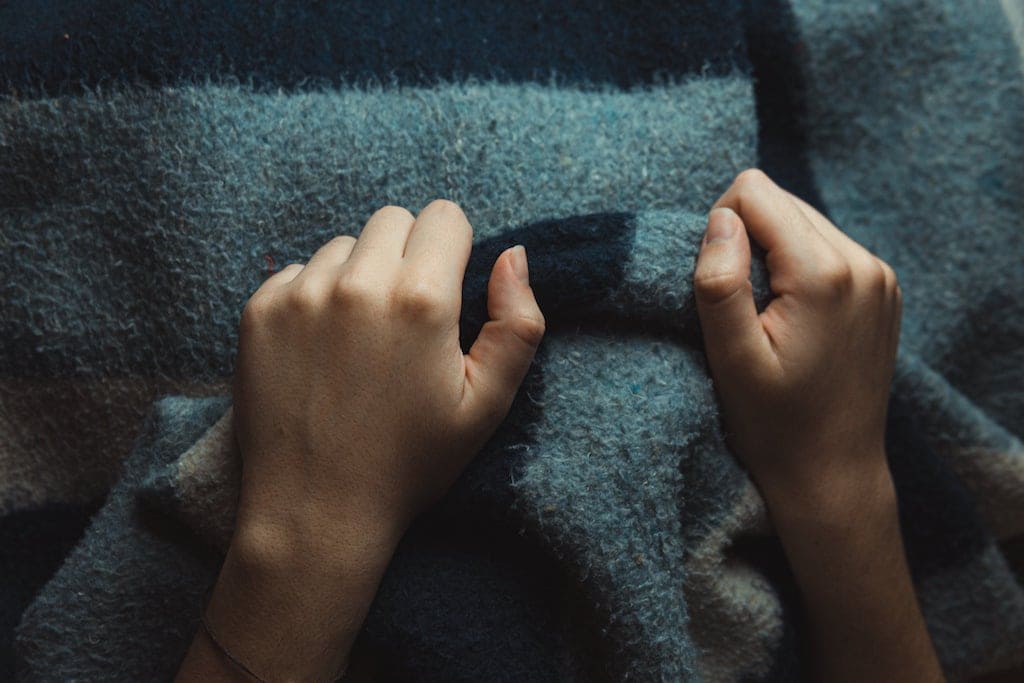 hands gripping a thick wool blanket