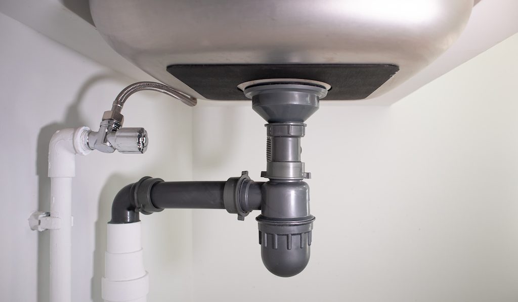 Water drain pipe under kitchen sink and faucet.