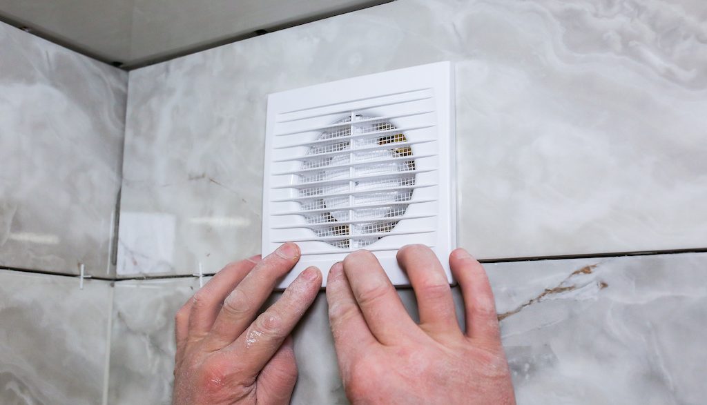 Man is making the wall bathroom fan vent. 