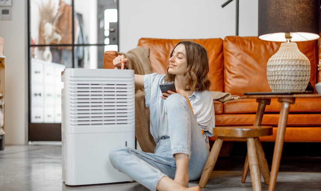 Woman sitting near air purifier and moisturizer appliance