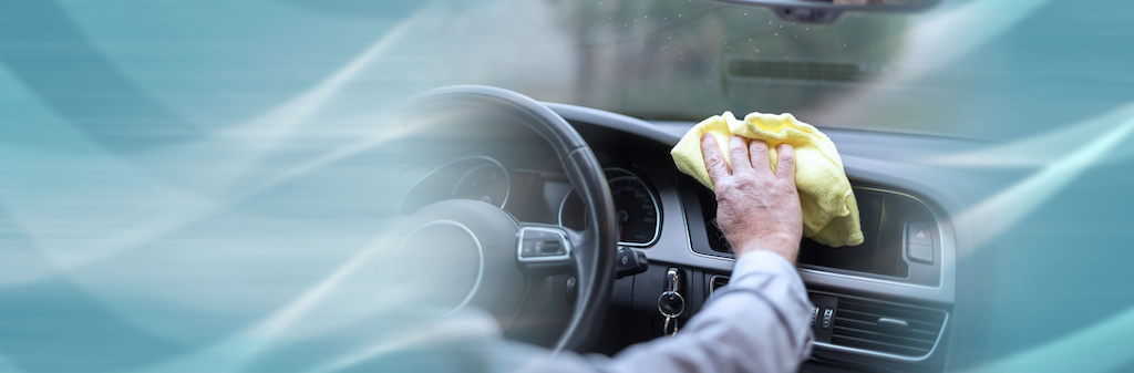 Man cleaning a car dashboard; panoramic banner