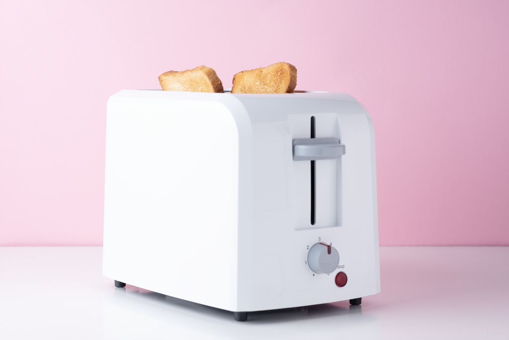 White toaster with roasted toast bread on pink background