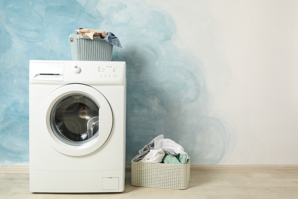 Laundry room with washing machine against blue wall, space for text