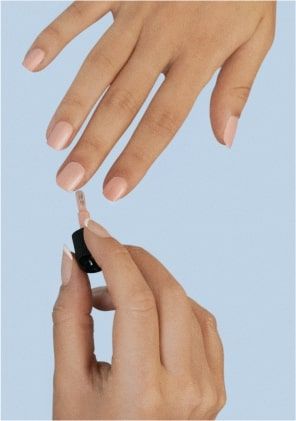 A beautician applies nail varnish to a customer's hands